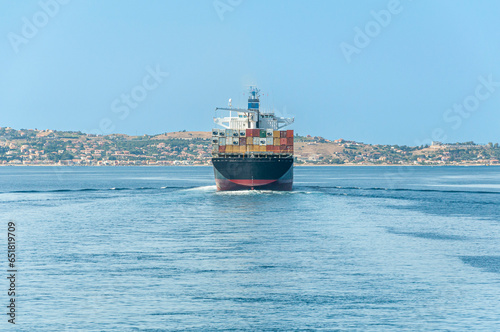 Vista di poppa di una nave portacontainer che attraversa lo Stretto di Messina