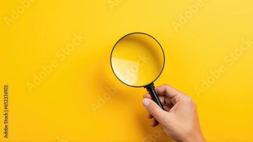 Hand holding magnifying glass on isolated yellow background