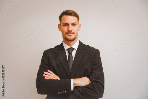Portrait of a young businessman standing with arms crossed isolated on white background in concept Successful, committed, and happy employees
