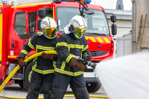 Pompiers devant un camion s'exerçant à lutter contre un incendie