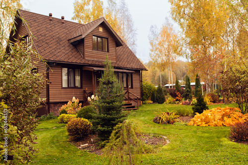 old rustic country house and autumn garden view. Bright hosta leaves, brown wooden lodge, natural style.