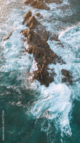Aerial view of ocean waves splashing on rocks