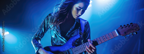 Young female musician playing guitar at a rock concert