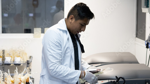 Young, Latino man with a friendly and professional appearance carrying out an automated process to separate whole blood into different therapeutic components for the benefit of patient