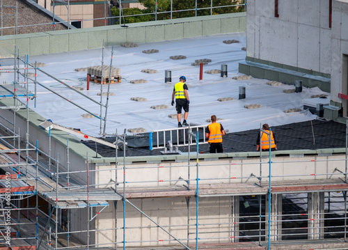 Birdseye view of roofer waterproofing the flat roof of a commercial building.