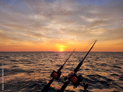 Fishing poles with sunrise glowing over Lake Michigan horizon