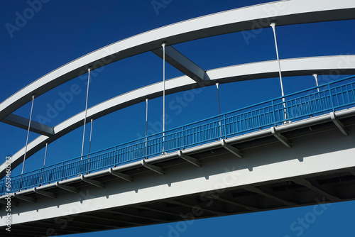 Road bridge with blue sky in the background. Straight road line with empty copy space. Brand new road barriers texture. Curvy construction bridge architecture. Arch bridge isolated on blue sky.