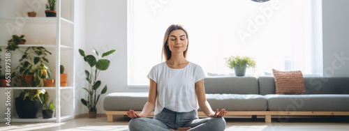 Young woman practicing lotus asana at home while meditating and smiling