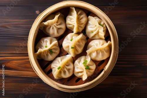 Top view of bamboo steamer containing momo dumplings on wooden background