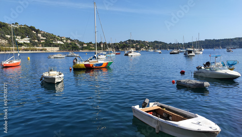 Villefranche-sur-Mer, France, October 2, 2021: View of Port Villefranche-Santé with boats, catamarans, sails boats, speed boats, and yachts moored to the pier, during daytime with a clear blue sky.