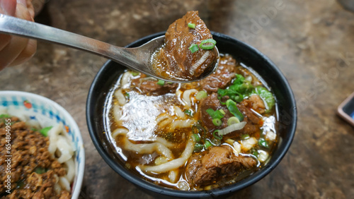 Beef noodles chili sauce served in a bowl on table top view of taiwanese food. Soup beef noodle in a bowl on wooden table. Chinese taiwanese cuisine
