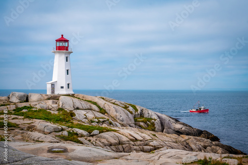 Iconic Peggy's Cove Lighthouse with red fisherman boat, Nova Scotia, Canada. Photo taken in September 2023.