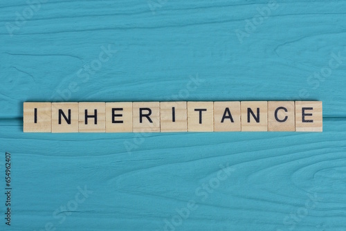 word inheritance made from wooden gray letters lies on a blue background