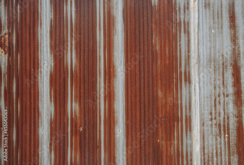 An old rusty metal sheet roof textured. Rust is an iron oxide formed by the reaction of iron and oxygen in the catalytic presence of water or air moisture.