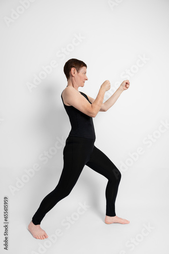 Paris, France - 09 30 2023: Athletic mature woman dressed in black, miming the sporty gesture of boxing.