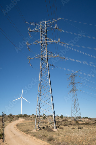 Vista de una linea electrica de alta tension con aerogenerador en un parque eolico.