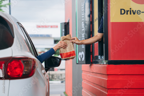 Young Man receiving coffee at drive thru counter., Drive thru and take away for protect covid19.