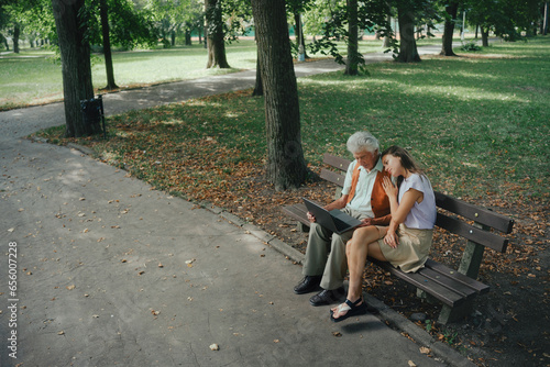 A widower is sitting on a bench in the park with his granddaughter, mourning his deceased wife.