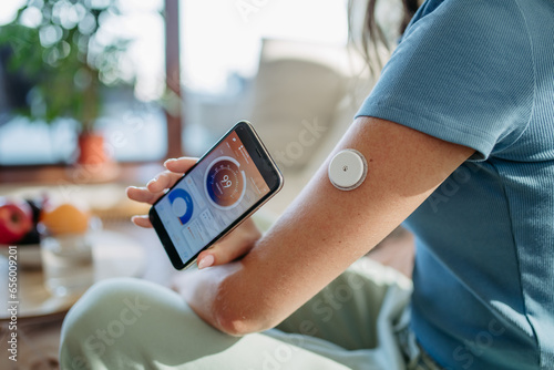 Woman with diabetes checking blood glucose level at home using continuous glucose monitor.