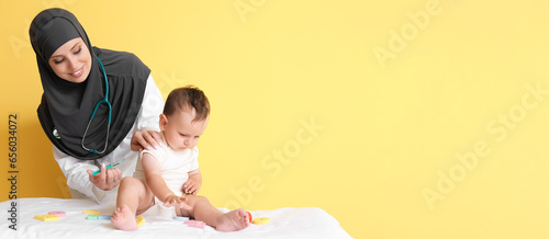 Muslim pediatrician vaccinating baby on yellow background with space for text