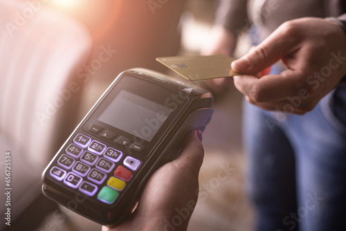 NFC credit card payment. Woman paying with contactless credit card with NFC technology. Wireless money transaction. Card machine in male hand on sunlight background