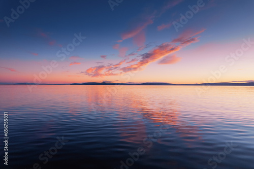 Blue cloudy sky over Burren mountains and reflection in dark water of Galway bay, Ireland. Blue hour nature scene. Nobody. Aerial view.