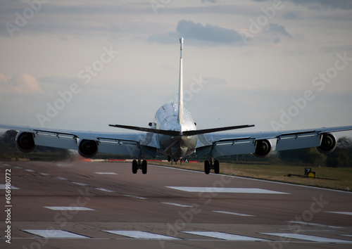 military raf rivet joint boeing RC-135 airplane in flight landing down on runway in sunset tail