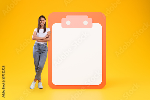 Smiling confident young caucasian lady with crossed arms near big plan list with free space