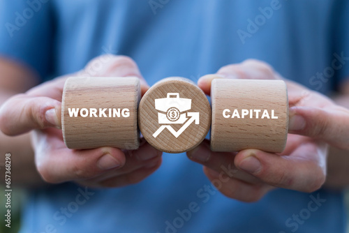 Hands holding wooden cylinders sees inscription: WORKING CAPITAL. Working capital business concept.