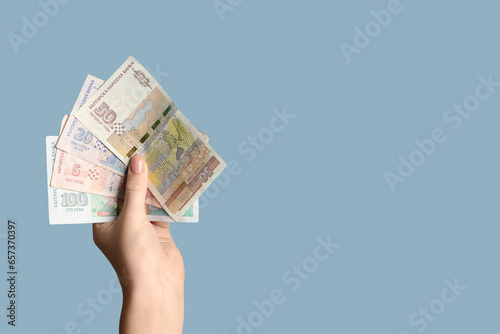 Female hand holding Bulgarian lev banknotes on blue background