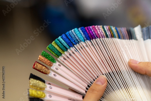 Collection of nails color polish samples. A palette of nail designs of different colors with gel polish. Transparent tips with nail polish samples. Demonstration fan-shaped palette of color shades.