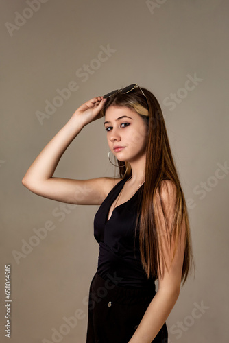 Lovely jew teenager girl in black clothes posing at grey background, serious looking at camera. Confident look of pretty jewish teen lady, studio shot. Generation Z youth concept. Copy ad text space
