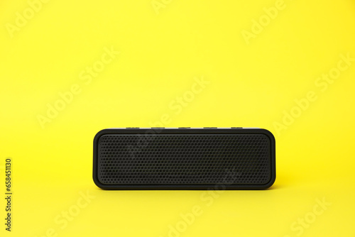 One portable bluetooth speaker on yellow background, space for text. Audio equipment