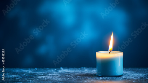 Une bougie allumée sur un table dans le cadre des fêtes de noël. En arrière plan, un fond bleu. 