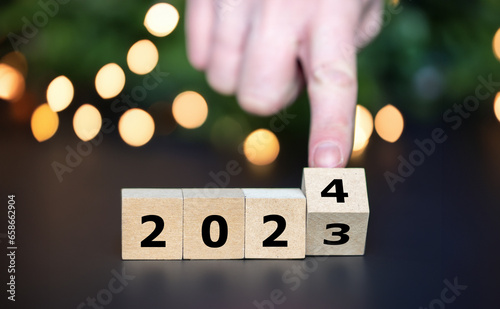 Hand turns cube and changes the year 2023 to year 2024..
