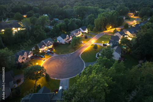 Aerial night view cul-de-sac road and spacious illuminated family houses in upstate New York suburban area. Real estate development in american suburbs