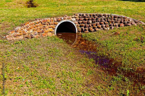Description Concrete culvert forming a grassy bridge over a drainage ditch with rock cladding near Riversdale in the Western Cape, South Africa