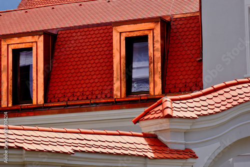 beavertail clay tile sloped residential roofs. bright shiny new copper plated roof dormers. new construction. closeup view. reflective glass window. mansard roof. modern house architecture. 