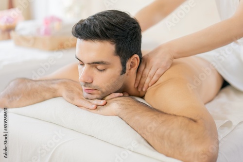 Spa and massage concept, Handsome young man receiving shoulder massage from masseur on table in spa salon.