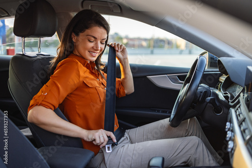 Young woman sitting on car seat and fastening seat belt, car safety concept. Woman fastens a seat belt in the car. Caucasian woman driver fastening car seat belt while sitting behind the wheel car.