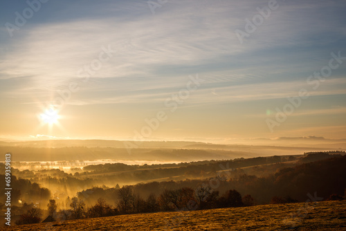 Fall landscape from above. Cold morning weather. Autumn mist with sunbeams over countryside during sunrise