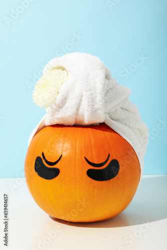 Skin and face care concept - pumpkin with eye patches and towel