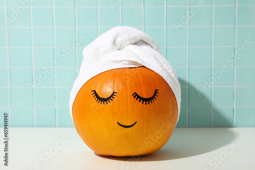 Skin and face care concept - pumpkin with eyelashes and towel