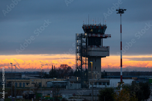 Airport control tower at Trieste airport during colorful sunset over city, Italy