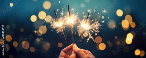 Person holding up three sparklers, bokeh background