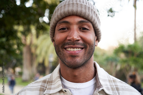 Portrait of multiethnic young man smiling and looking at camera. Friendly happy African American male person outdoors. Close up.