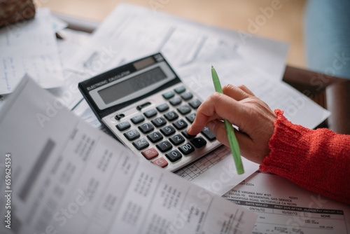 The hands of an elderly woman with a calculator and a lot of utility bills. Pensioner and payment of utilities for heating