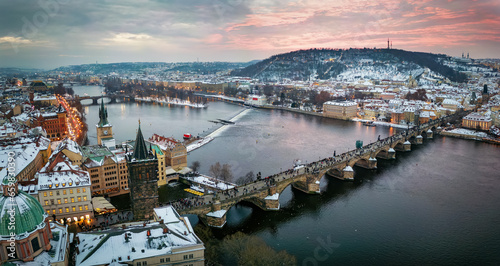 Panoramic view of the snow covered cityscape of Prague, Czech Republic, with Charles Bridge and the old town during winter sunset time