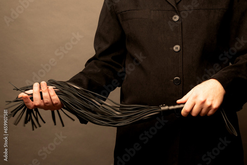 male dominant holds a leather whip Flogger for hard BDSM sex with spanking