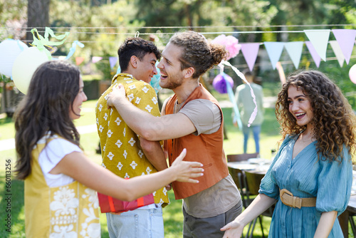 Friends reunite after a long time apart. Men and women embracing, happy to meet at garden party.